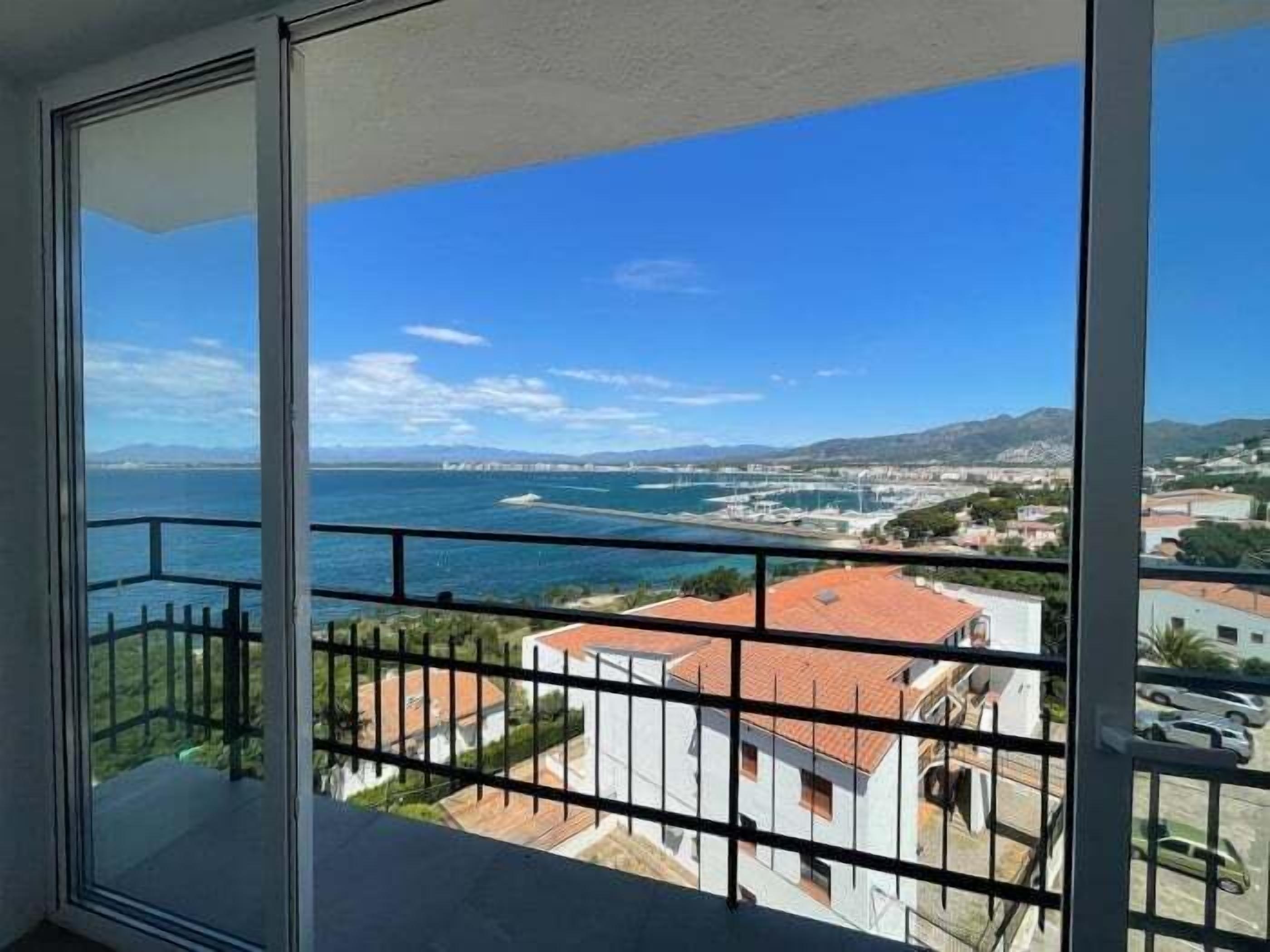 A balcony with a clear view of the sea and a coastal town.