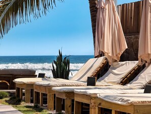 Fila de sillones de madera con cojines color beige, ubicados en una terraza con vista al océano.