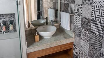 A bathroom with a large mirror, a vessel sink, and patterned tiles on the walls.