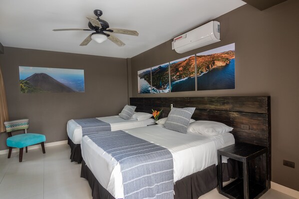 A bedroom with two beds, a ceiling fan, an air conditioner, and wall art depicting landscapes.