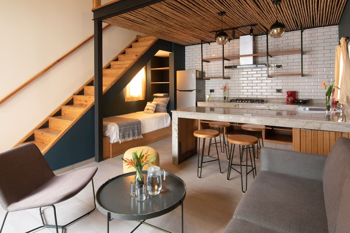 A compact apartment with a kitchen, dining area, and a small bedroom with a staircase.