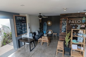A cozy lounge area with a chalkboard menu, a surfboard, and a wooden shelf with items.
