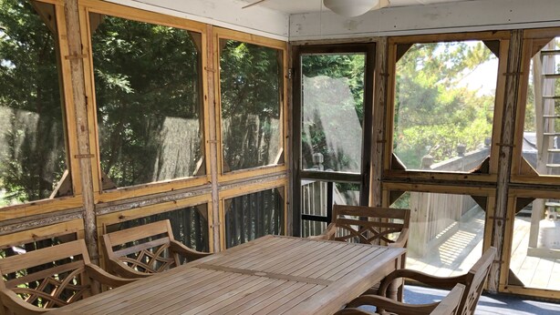 Ein Holzespeisetisch mit Stühlen, große Fenster und ein Deckenventilator.