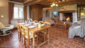 A rustic interior with a wooden dining table set for four, a sofa, and a fireplace. - Character house in Crouttes with fireplace and pets allowed (Crouttes)