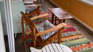 Una stanza luminosa con sedie in legno, un tavolo, ampie finestre e un tappeto colorato.
