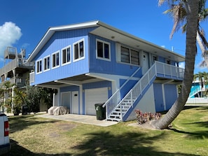 A two-story house with a blue exterior, a covered front porch, and a staircase leading to the upper floor.