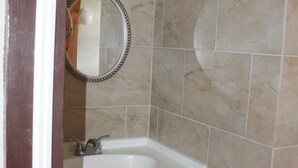 A bathroom with a white sink, wooden cabinets, a mirror, and beige tiled walls.