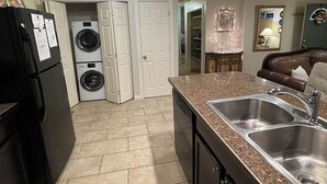 A kitchen with a refrigerator, washing machine, and a sink.