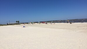 A wide sandy beach with a clear blue sky.