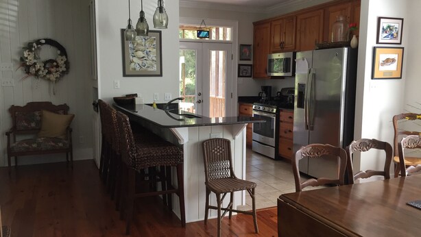 A kitchen with a central island, wooden cabinets, stainless steel appliances, and a dining area with wicker chairs.