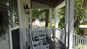 A porch with white rocking chairs and a lantern.