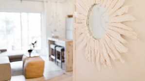 Un intérieur moderne agrémenté d’une œuvre d’art murale originale, d’un coin repas en bois et d’une cuisine en arrière-plan.