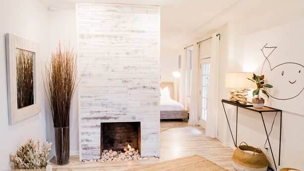 Un intérieur moderne avec une cheminée, un lit et une décoration minimaliste.