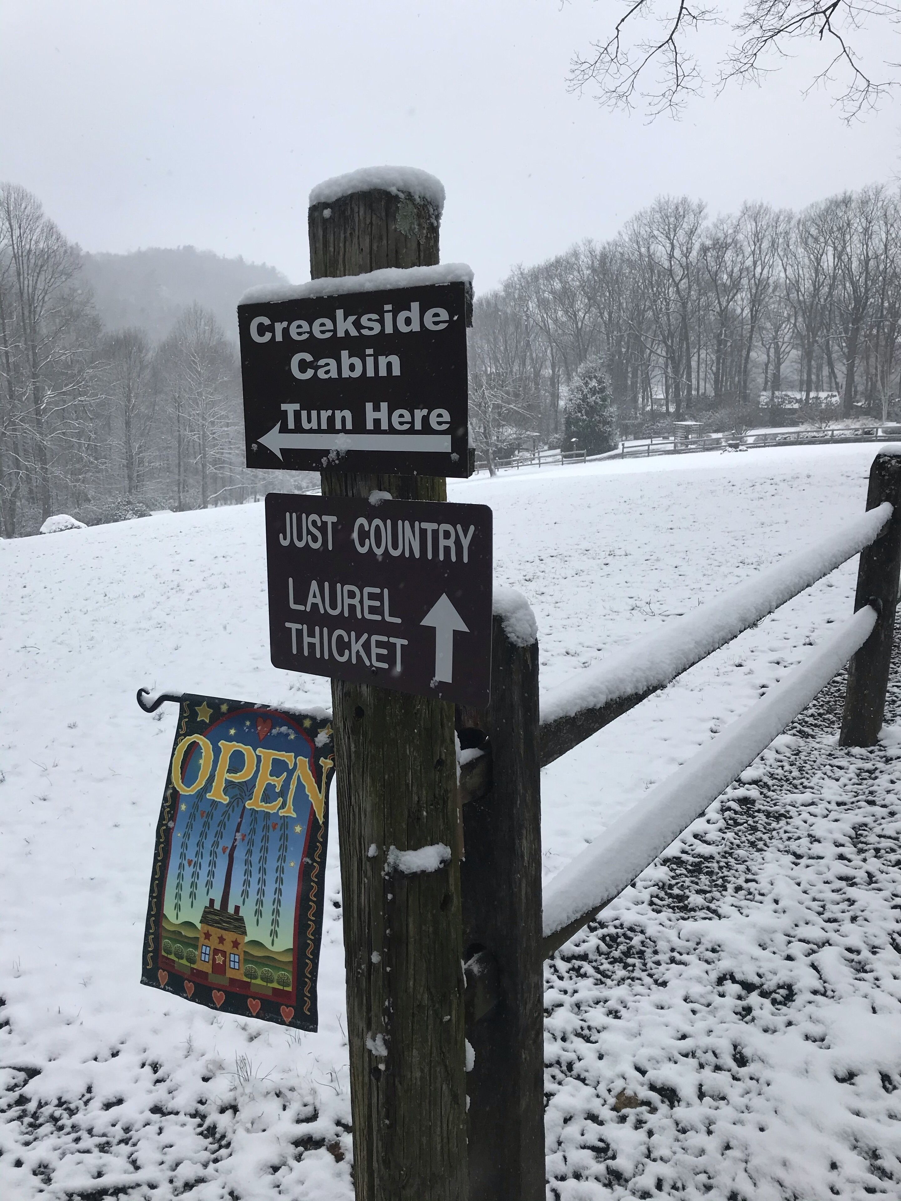 Un poste de madera con indicaciones para Creekside Cabin y Just Country Laurel Thicket.