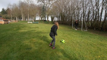 A grassy outdoor area with a goalpost and a soccer ball.
