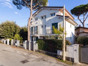 A two-story residential building with a balcony, surrounded by a gated fence and trees. - Michelangelo II by Interhome (Marina Pietrasanta)