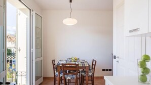En matplats med ett bord dukat för fyra personer, en hängande lampa och utsikt genom en öppen dörr ut mot omgivningen.