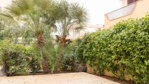 Un patio con palmeras, setos y un patio de baldosas.