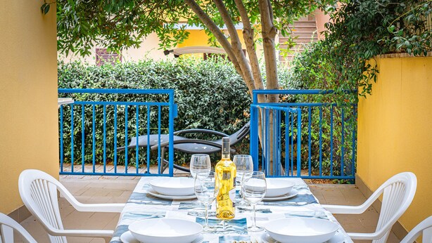 Mesa lista para comer al aire libre, con una valla azul y paredes amarillas al fondo.