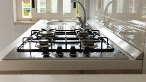 Una cocina moderna con estufa a gas, pileta de acero inoxidable y ventana que proporciona luz natural.