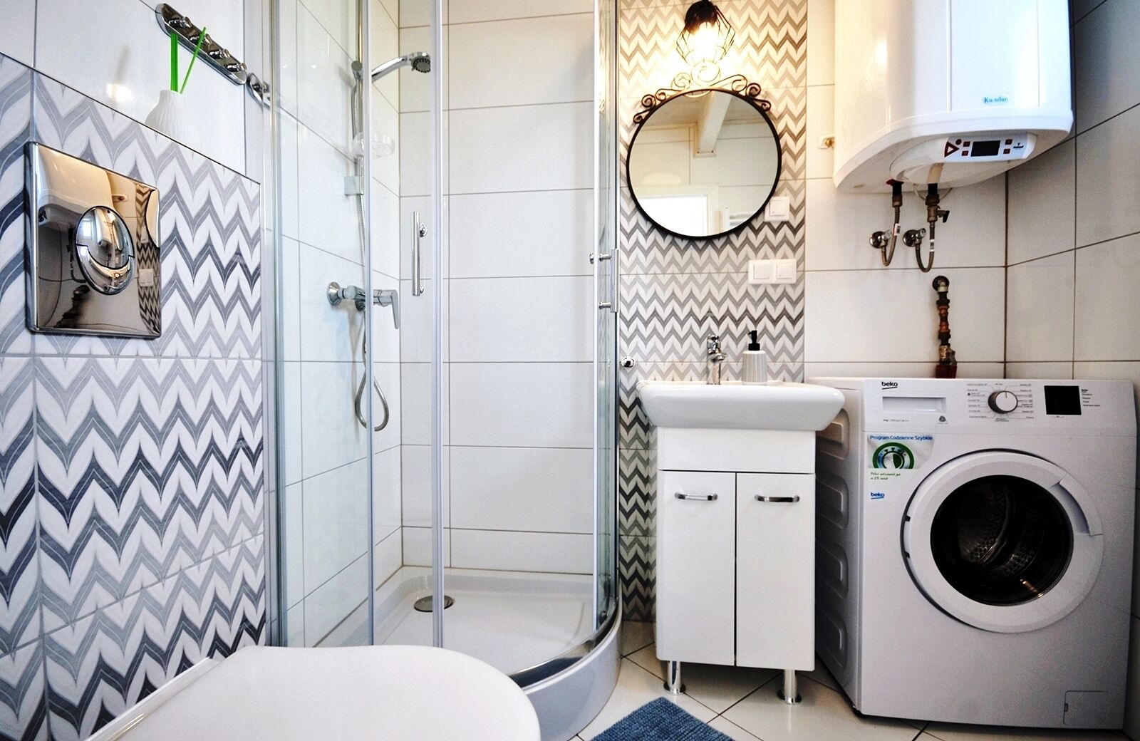 A modern bathroom with a shower, a sink, a mirror, and a washing machine.