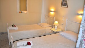 Et hotelværelse med to senge, hver med en pude og et natbord med en lampe.