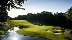 A golf course with a pond, sand bunkers, and a path. - Year round fun close to lakes, golf, and ski! (Bellaire)