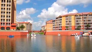 A waterfront hotel with multiple buildings, a bridge, and boats on the water.