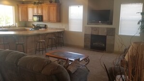 A kitchen with wooden cabinets, a central island with bar stools, a fireplace, and a TV mounted above it. - Las Palmas. Great place for a getaway (St. George)