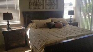 A bedroom with a large bed, two bedside tables with lamps, a wooden headboard, and a window with blinds. - Las Palmas. Great place for a getaway (St. George)
