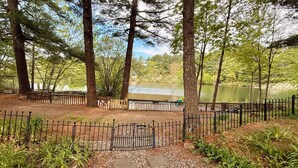A pathway leading to a lake with a wooden fence and a sign indicating a dog park.