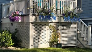 A house with a covered porch, white railings, and potted plants.