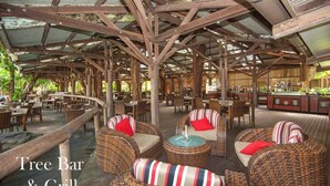Un bar restaurante con mobiliario de mimbre y terraza de madera.