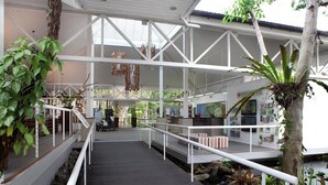 Una terraza de madera con barandas blancas que conduce a un espacio cubierto con asientos y vistas al agua.