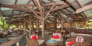 Un bar restaurante con mobiliario de mimbre y terraza de madera.