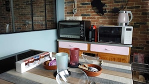 Una cocina con pared de ladrillo, microondas, tostadora y cafetera sobre la encimera.