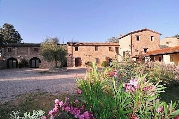 A courtyard with stone buildings, arched doorways, and a gravel path.