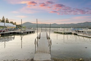 A marina with docks and boats, surrounded by calm water and distant mountains.