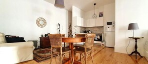 A modern living room with a sofa, a dining table with chairs, a coffee table, and a lamp.