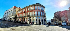 A historic building with a curved facade, large windows, and a cobblestone street in front. - Dom Luis Apartment in the historic center (Porto)