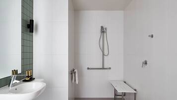 A modern bathroom with a white sink, a handheld showerhead, a towel rack, and a small bench.