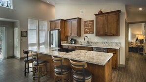 Une cuisine moderne avec des meubles en bois, un plan de travail en granit et un îlot central doté de tabourets de bar.