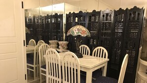 A dining area with a white table and chairs, a decorative umbrella, and a black partition with intricate designs. - Luxury flat, close to city center (Zografou Athens)