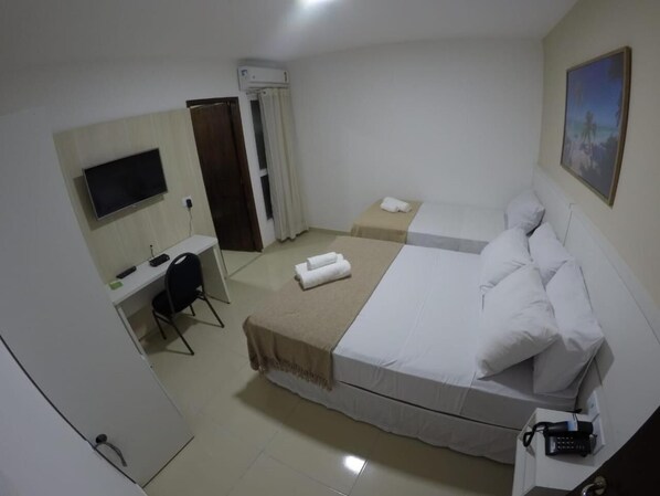 A hotel room with a bed, a desk, a chair, a TV, and a bathroom. - Pousada Kanoas Maragogi (Maragogi)