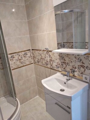 Un baño con ducha, lavabo y espejo.