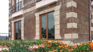 A multi-story building with a brick facade, large windows, and a balcony with metal railings. - Tepedeki Ev Apart (Gomec)