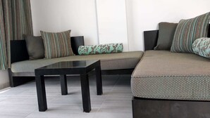 A modern living room with a sectional sofa, a coffee table, and patterned cushions. - Tepedeki Ev Apart (Gomec)