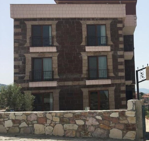 Un edificio de varios pisos con fachada de piedra, varios balcones y un letrero que indica un servicio de alquiler de bicicletas.
