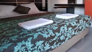 A neatly made bed with a patterned bedspread and two folded white towels. - Tepedeki Ev Apart (Gomec)