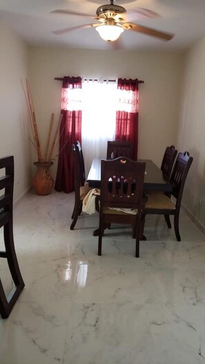 Enjoy meals in this cozy dining area with a table and four chairs, a ceiling fan, and a potted plant.
